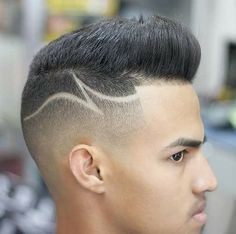 Close-up of a person's head showcasing a stylish haircut with shaved sides and intricate design patterns.